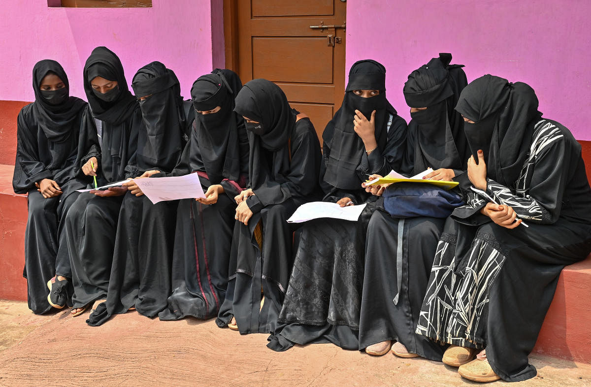 Students of Government First Grade College in Kavoor sit in front of a house situated near the college on Wednesday. DH photo