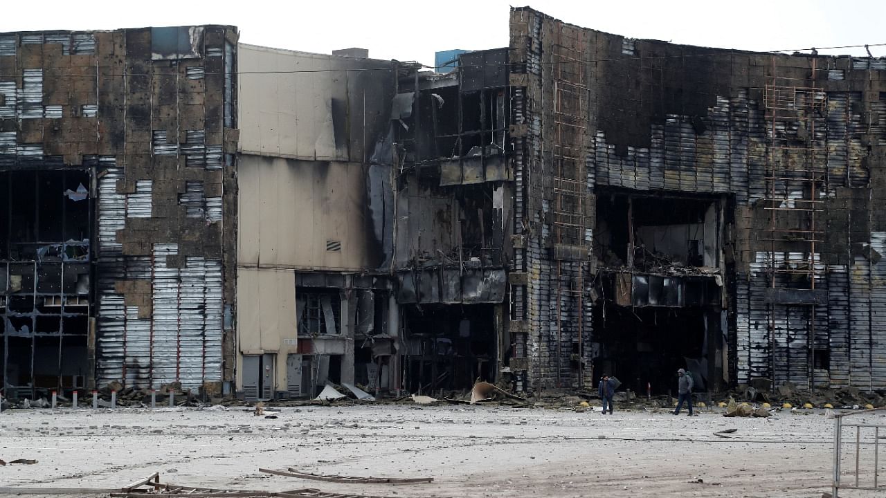 People walk near a building, which was destroyed during Ukraine-Russia conflict in the besieged southern port city of Mariupol. Credit: Reuters photo
