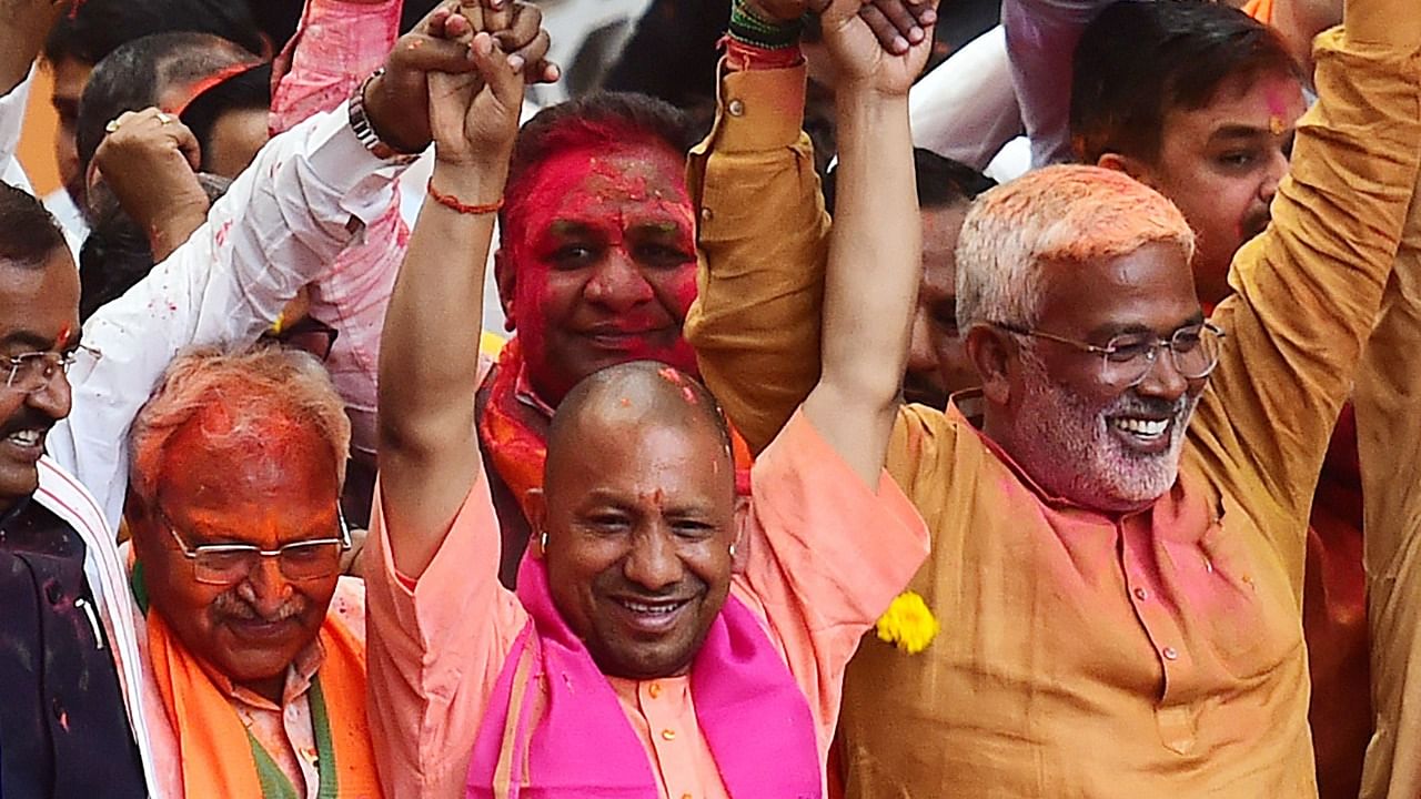 Chief Minister of Uttar Pradesh Yogi Adityanath (wearing pink scarf) gestures to his supporters after Bharatiya Janata Party's (BJP) win in the state assembly elections at the party office in Lucknow on March 10, 2022. Credit: AFP Photo