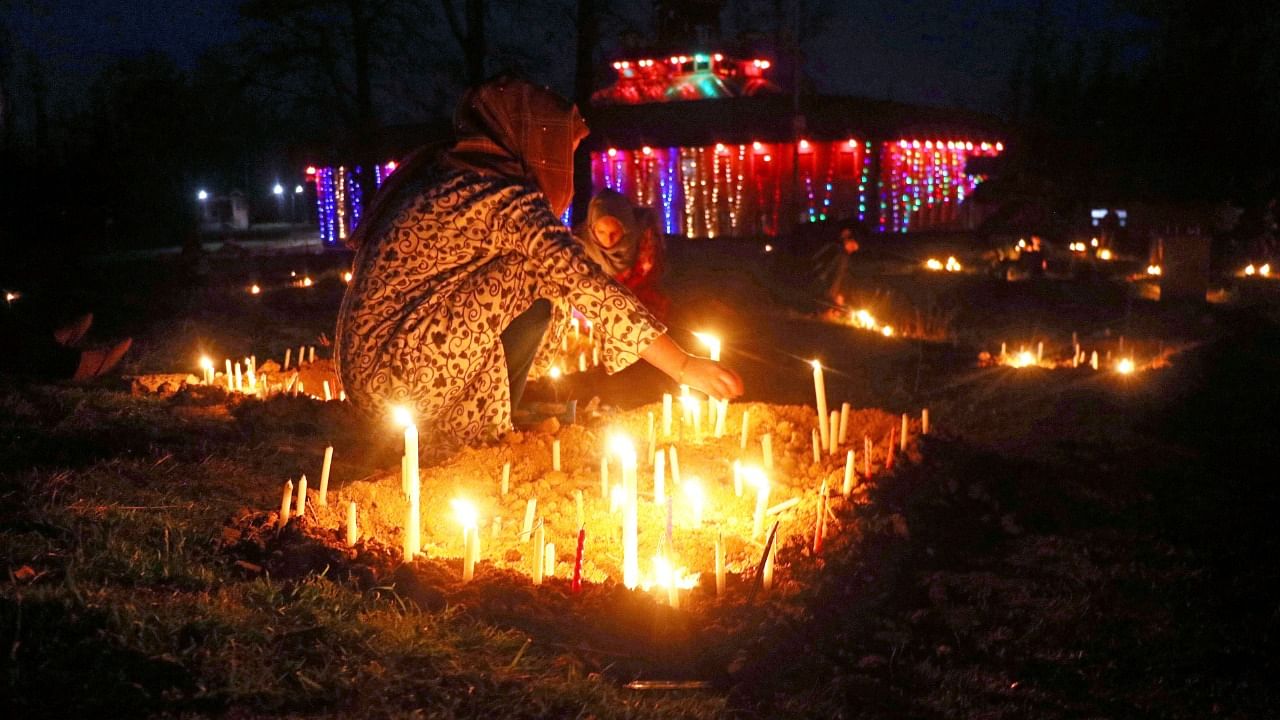 Kashmiri Shia Muslim girls light candles at the grave of their relatives on the occasion of Shab-e- Barat, on the outskirts of Srinagar, Friday, March 18, 2022. On Shab-e- Barat Muslims visit ancestral graveyards during nighttime to pray for the salvation of the souls of the departed. Credit: PTI Photo