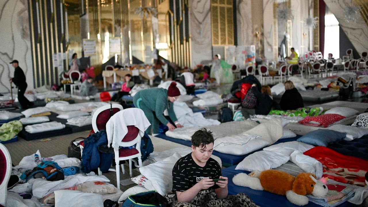 Ukrainian refugees rest at a hotel ballroom converted into a makeshift shelter in the town of Suceava, Romania. Credit: AFP Photo