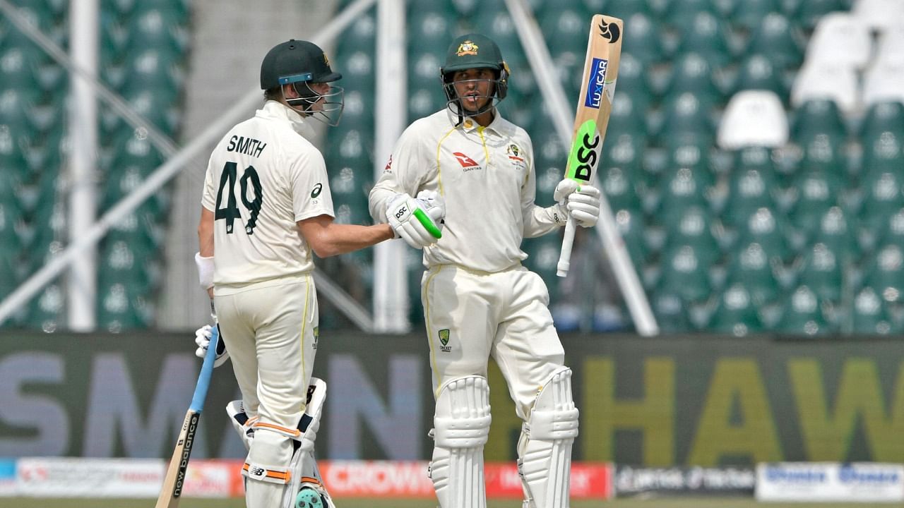 Australia's Usman Khawaja (R) celebrates with teammate Steve Smith after scoring a half-century during the first day of the third and final Test against Pakistan at the Gaddafi Cricket Stadium in Lahore. Credit: AFP Photo