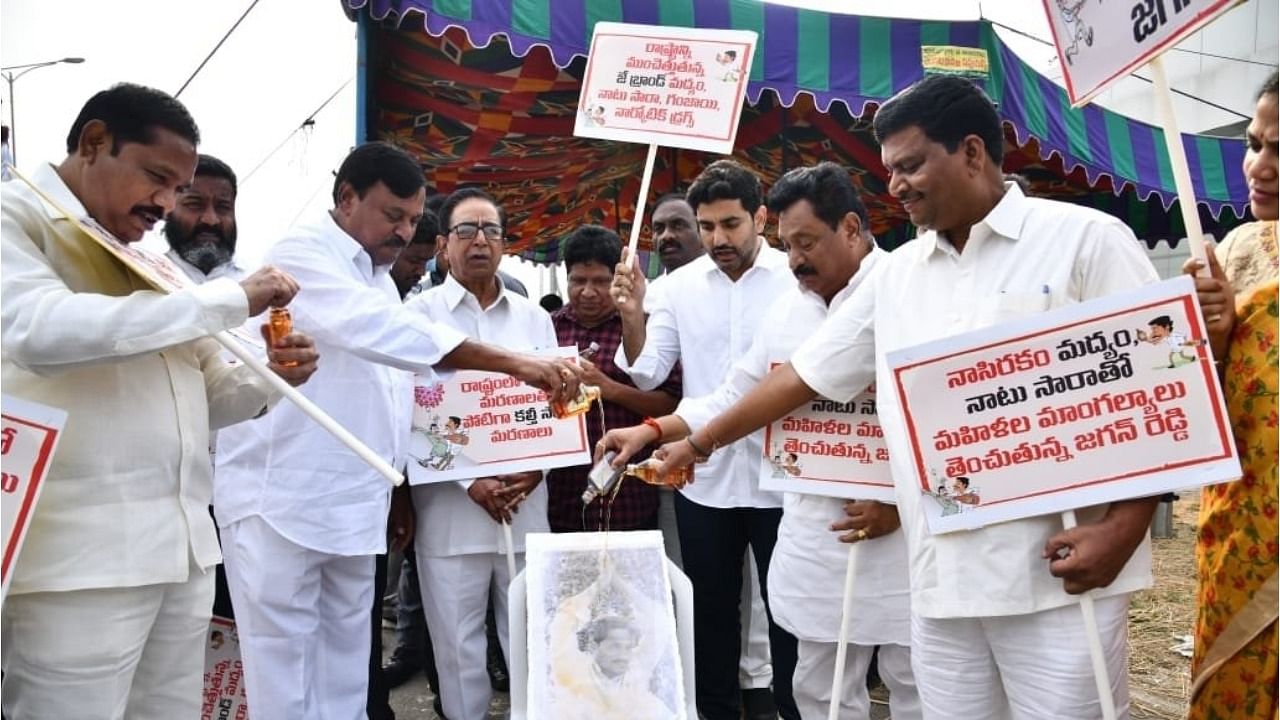 TDP legislators wash Andhra CM's portrait with liquor. Credit: IANS Photo