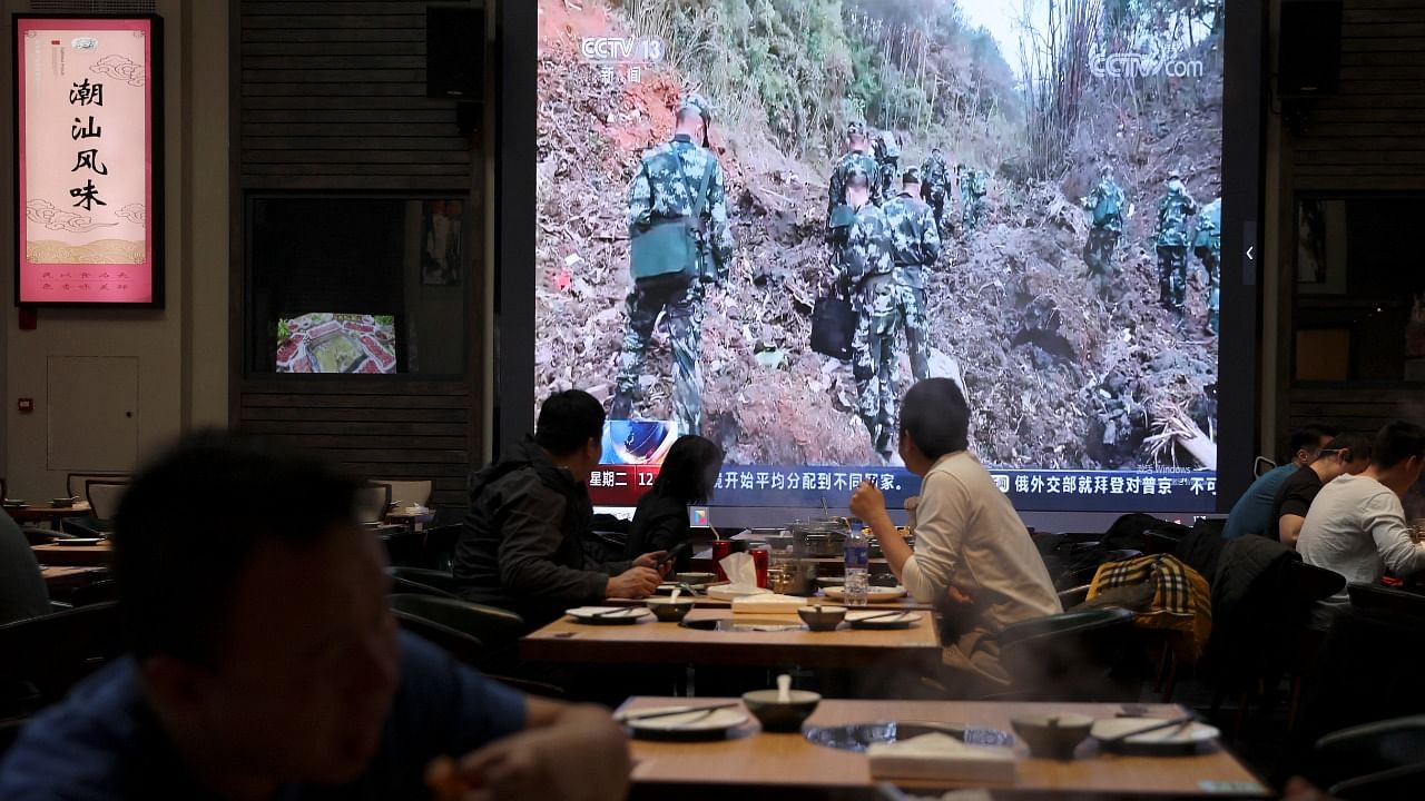 Customers dine as they watch a screen showing news footage of paramilitary police officers working at the site where a China Eastern Airlines Boeing 737-800 plane flying from Kunming to Guangzhou crashed. Credit: Reuters Photo