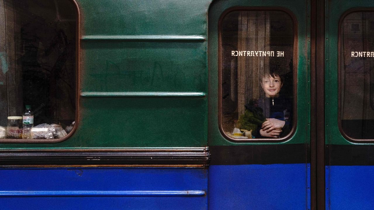A young boy looks through a subway window as he shelters from attacks in a metro station of Kharkiv. Credit: AFP File Photo