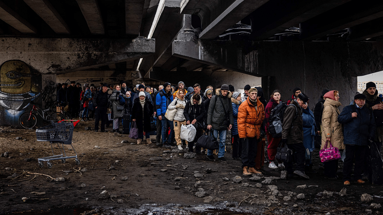 Evacuees stand under a destroyed bridge as they flee the city of Irpin, northwest of Kyiv. Credit: AFP Photo