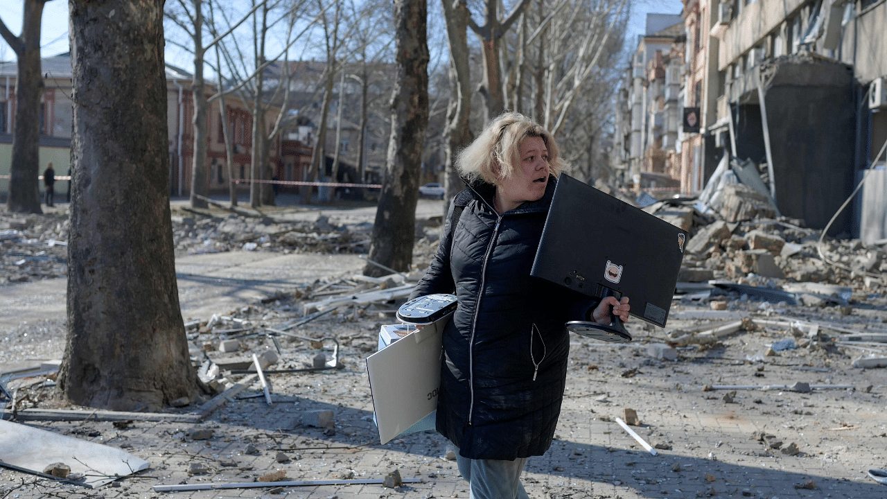 A woman carries her belongings from a building hit by a Russian rocket in Mykolaiv,. Credit: AFP Photo