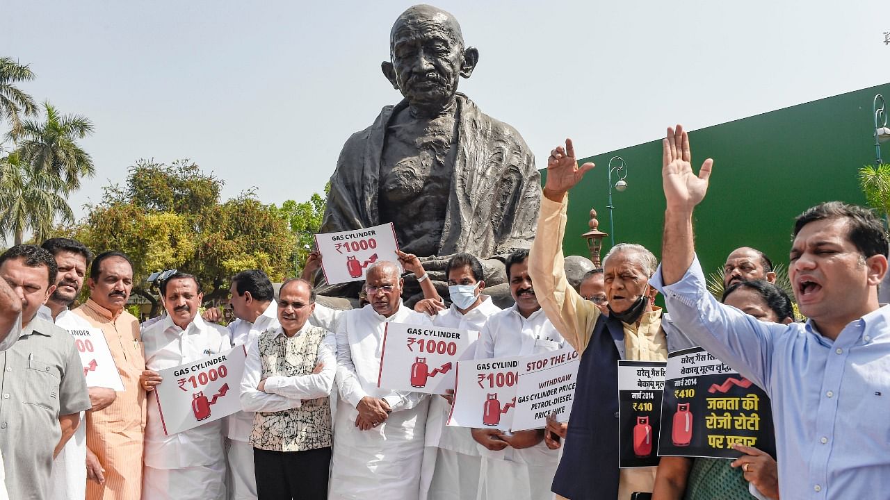 Congress MPs holding placards protest over the increase in the prices of LPG cylinder and petrol & diesel in front of Mahatama Gandhi statue at Parliament House, in New Delhi. Credit: PTI Photo