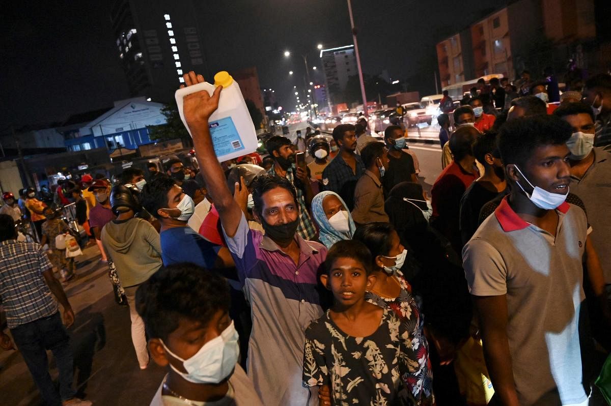 People waiting to buy kerosene oil for cooking stop traffic along a main road in Colombo on March 22, 2022, after a fuel station ran out of kerosene. Credit: AFP Photo