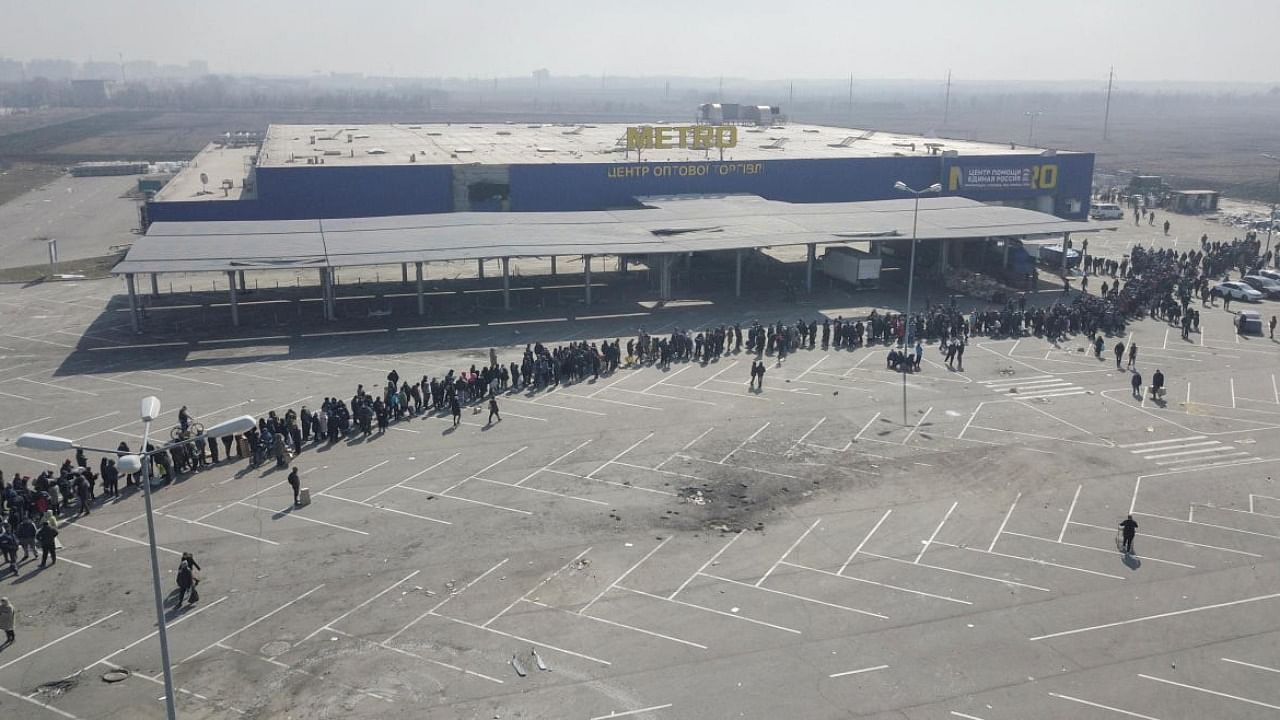 People stand in a long queue during the distribution of humanitarian aid near a damaged store of wholesaler Metro in the course of Ukraine-Russia conflict in the besieged southern port city of Mariupol. Credit: Reuters photo