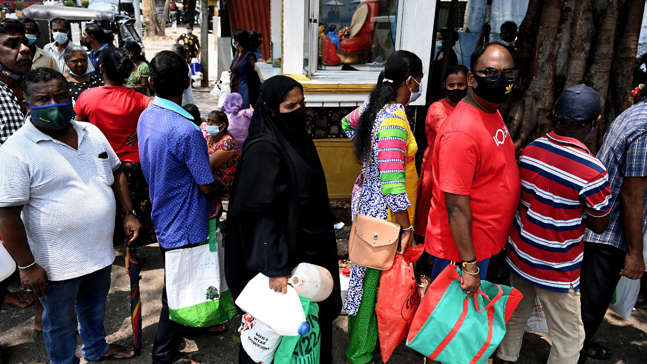 People stand in a queue to buy kerosene oil for home use at a petrol station in Colombo. Credit: AFP Photo