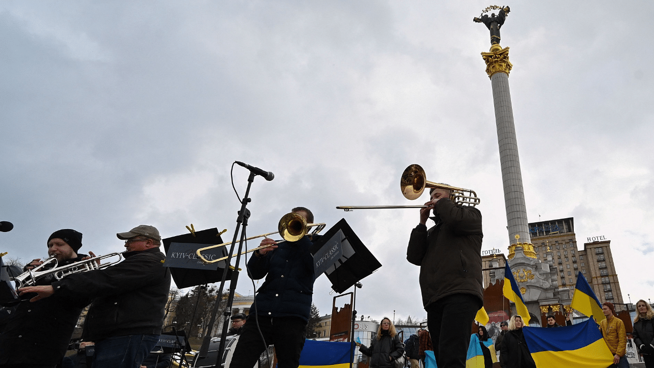Spectators hold the Ukrainian flags as Musicians of the Kyiv-Classic Symphony Orchestra under the direction of conductor, UNESCO Peace Artist Herman Makarenko perform at Independence Square in Kyiv. Credit: AFP Photo