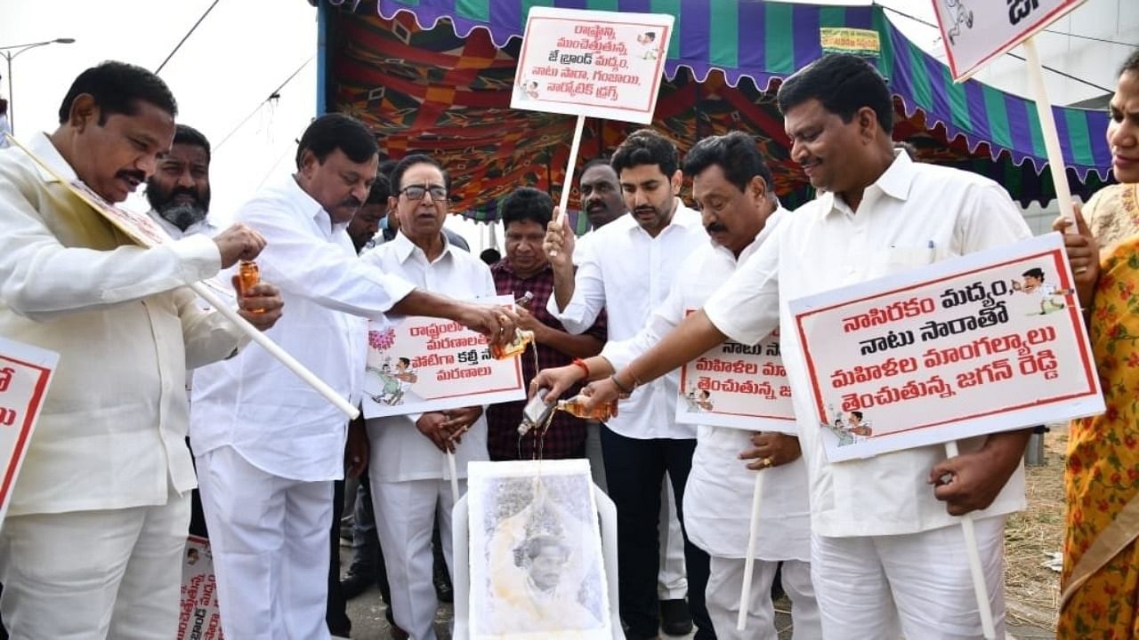 TDP legislators wash Andhra CM's portrait with liquor. Credit: IANS Photo