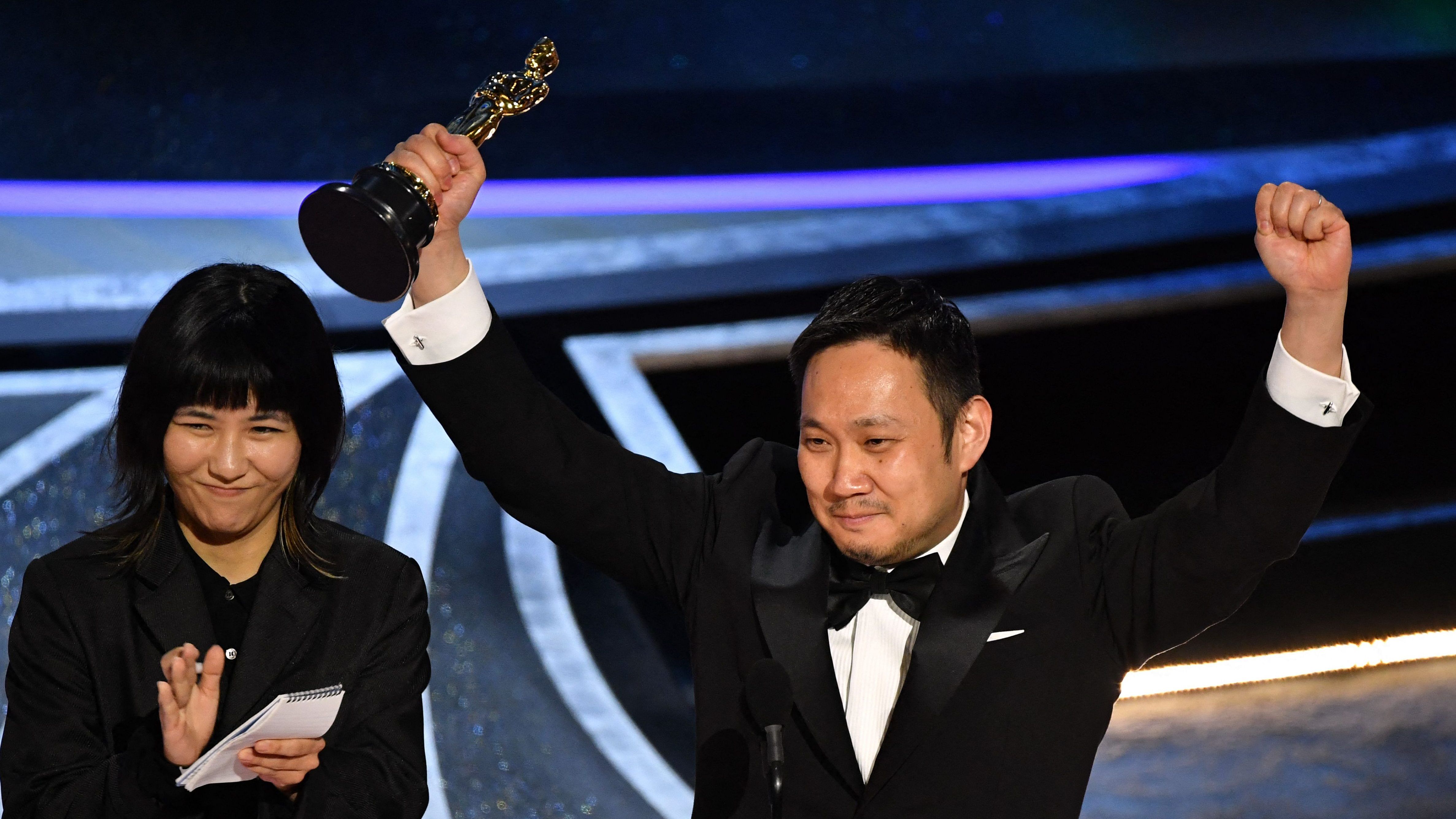 Japanese director Ryusuke Hamaguchi (R)accepts the award for Best International Feature Film for "Drive My Car" onstage during the 94th Oscars at the Dolby Theatre in Hollywood. Credit: AFP Photo