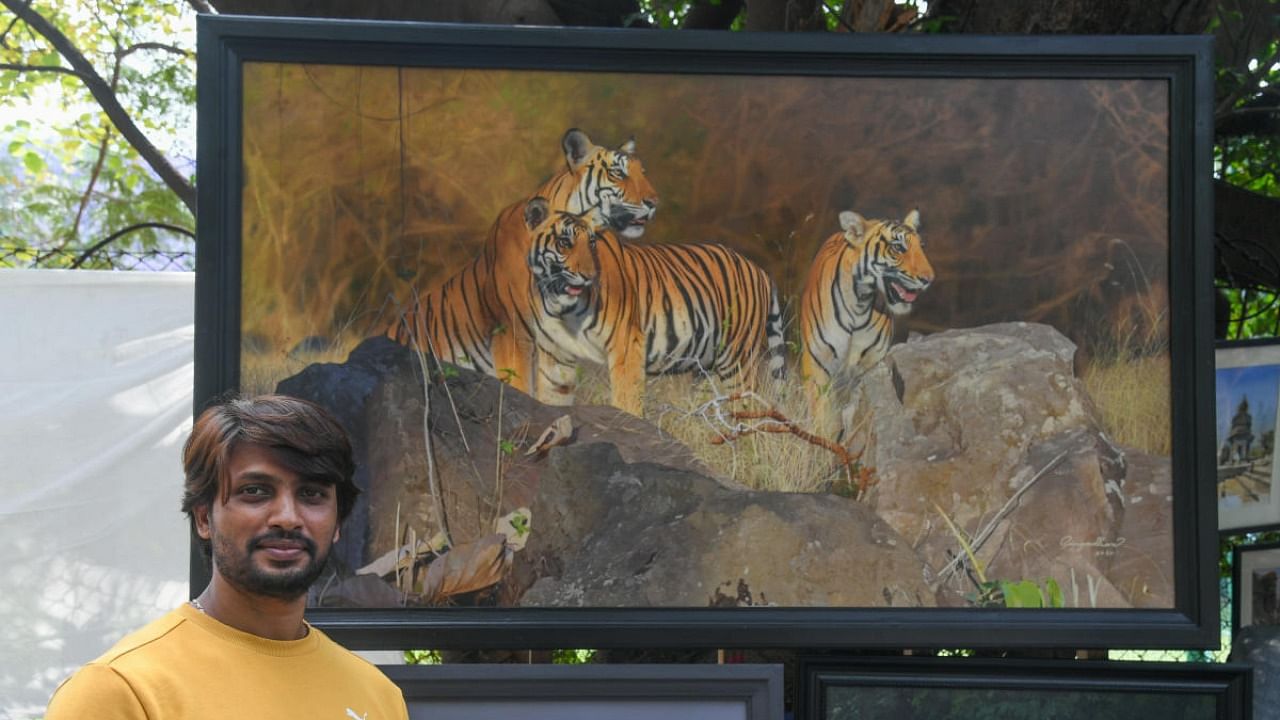 Gangadhar with his oil painting entitled 'Kabini Monarch', which went for Rs 8 lakh at Chitra Santhe, in Bengaluru on Sunday. Credit: DH Photo/S K Dinesh