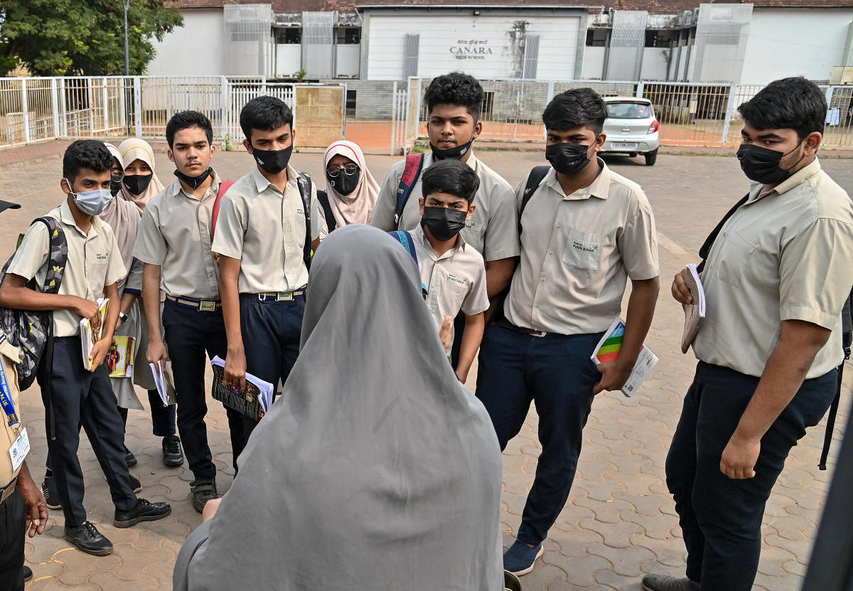 A teacher gives last-minute instructions to students outside the examination centre at Canara School in Dongarkeri. DH Photo