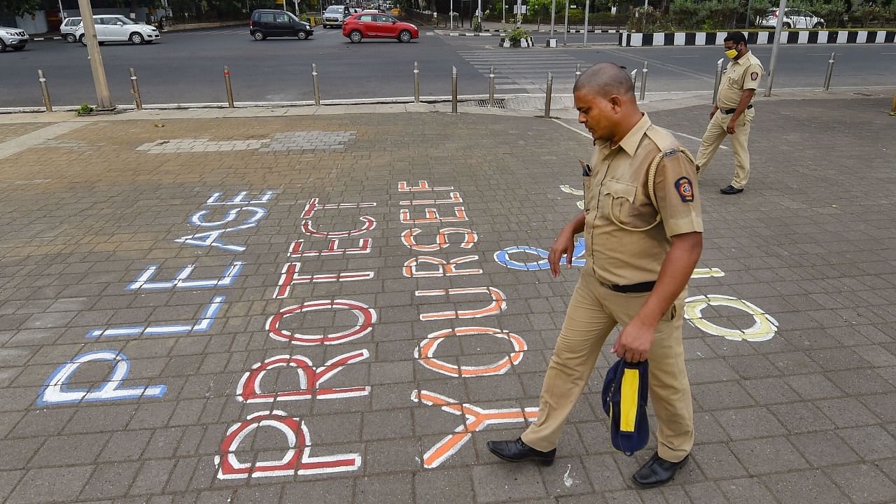 olice personnel walk past a painted message that reads 'Please Protect Yourself And Others' at Marine Drive in Mumbai. Credit: PTI File Photo