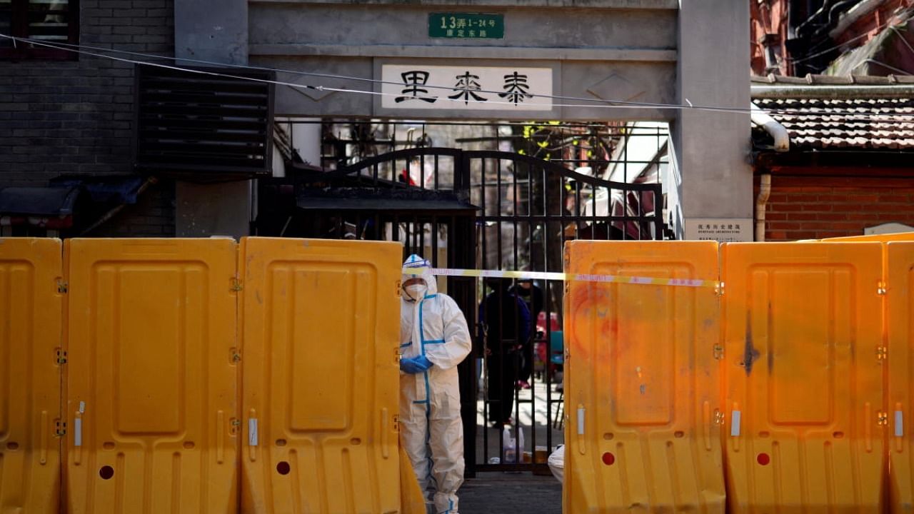 A worker in a protective suit stands behind barriers sealing off a residential area under lockdown, following the coronavirus disease outbreak in Shanghai, China March 29, 2022. Credit: Reuters Photo