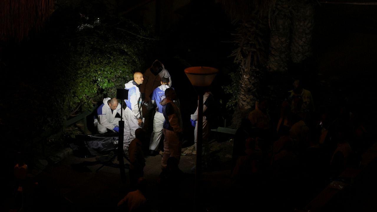 Israeli police forensics experts surround a body at the scene of an attack in which people were killed by a gunman on a street near Tel Aviv. Credit: Reuters Photo