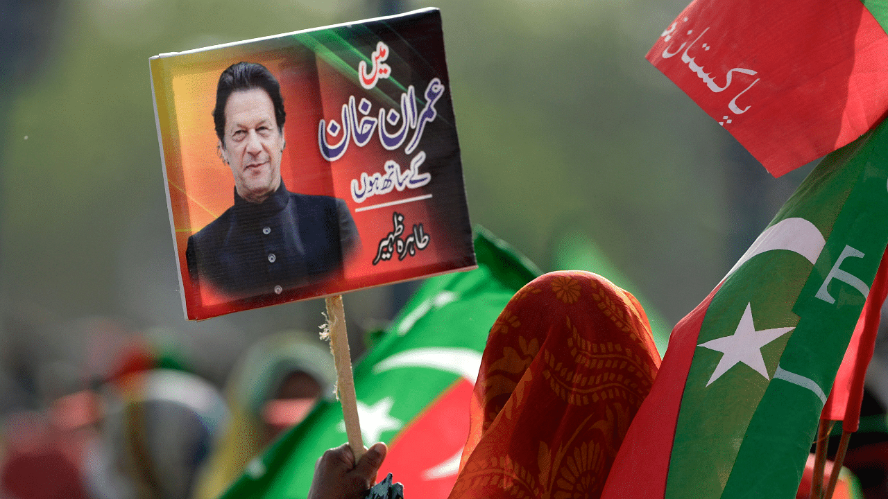 A supporter of ruling Pakistan Tehreek-e-Insaf (PTI) party holds a placard with a picture of Pakistan's Prime Minister Imran Khan. Credit: AFP Photo