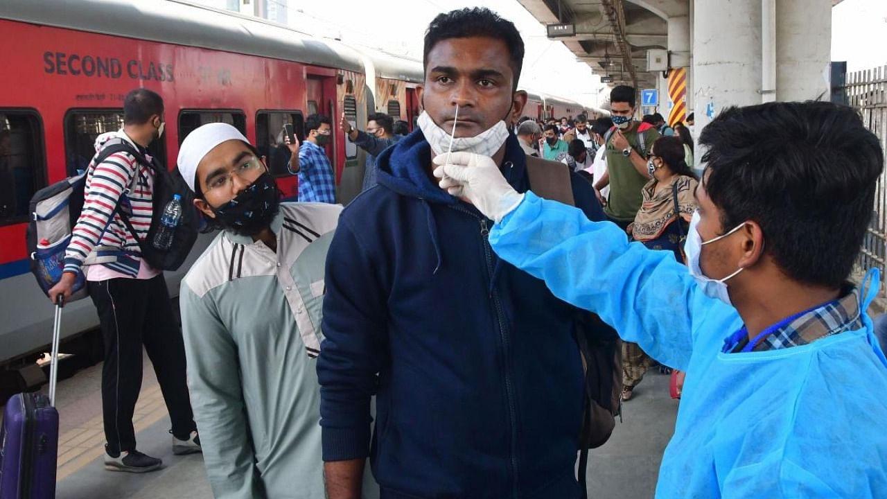 A Brihanmumbai Municipal Corporation (BMC) health worker collect swab samples of an out station passenger for Covid-19 test, at Dadar railway station in Mumbai. Credit: PTI Photo