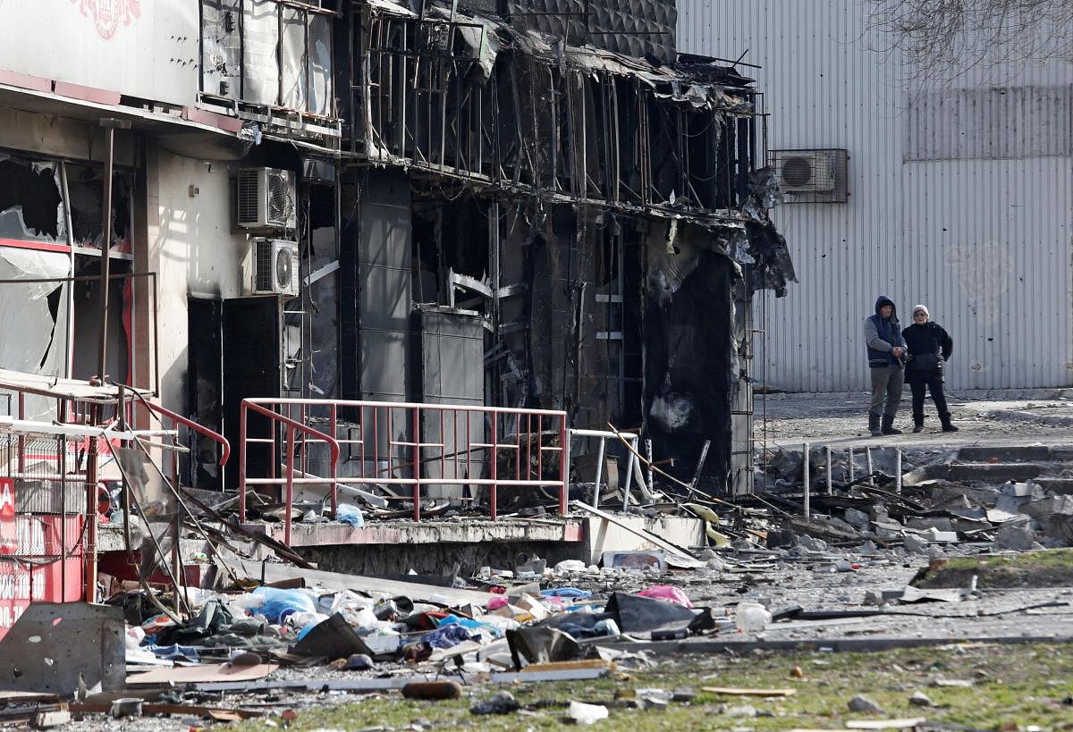 Local residents stand next to a damaged building in Mariupol. Credit; Reuters Photo