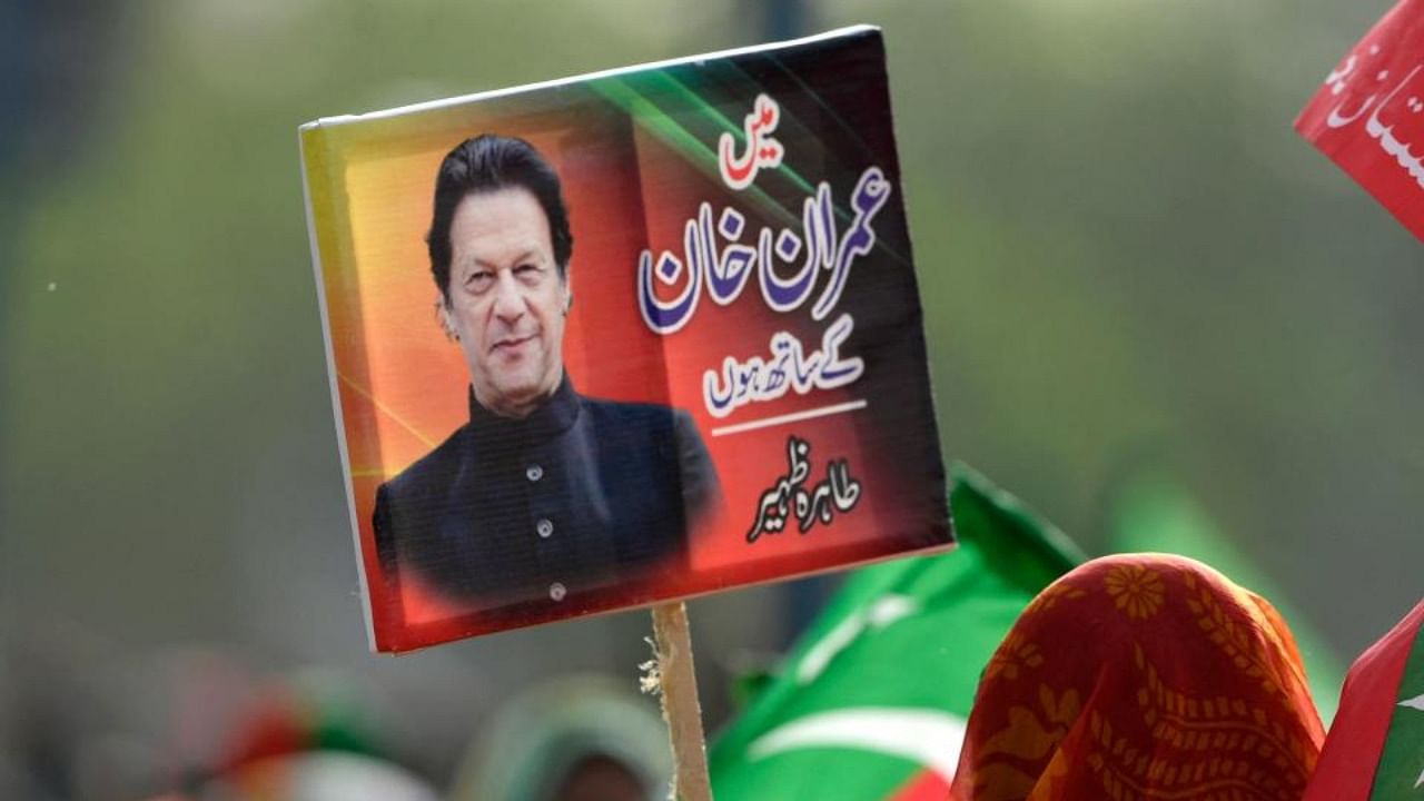 A supporter of ruling Pakistan Tehreek-e-Insaf (PTI) party holds a placard with a picture of Pakistan's Prime Minister Imran Khan during a rally in Islamabad on March 27, 2022. Credit: AFP Photo