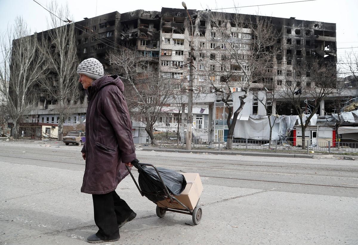 An elderly woman crosses a street near a building damaged in the course of Ukraine-Russia conflict in the southern port city of Mariupol. Credit: Reuters Photo