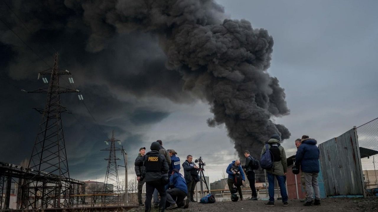 Journalists and residents stand as smoke rises after an attack by Russian army in Odessa. Credit: AFP Photo