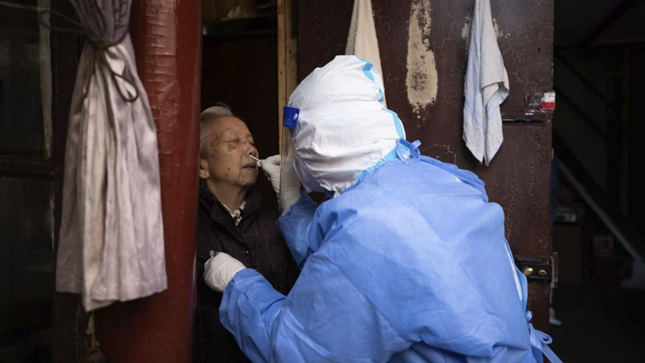 In this photo released by Xinhua News Agency, a medical worker conducts antigen testing for an elder resident in Shanghai, China, on Sunday, April 3, 2022. Credit: AP/PTI Photo