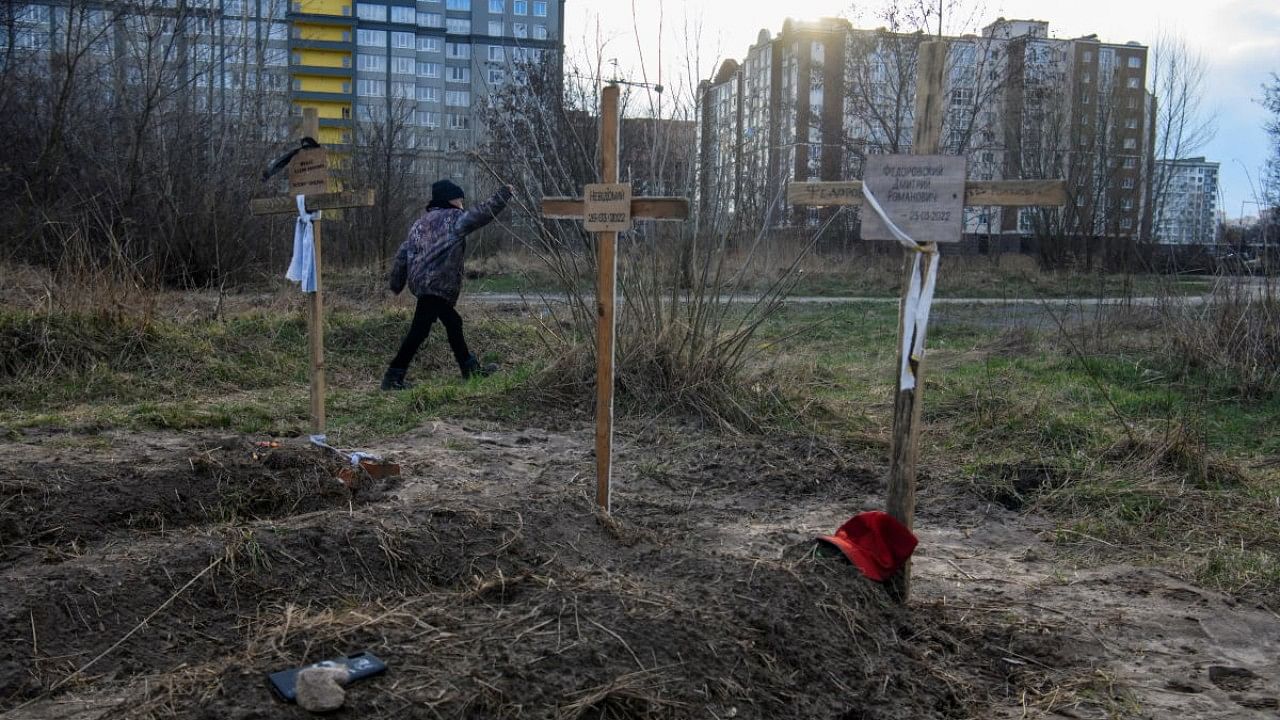 A boy walks past graves with bodies of civilians, who according to local residents were killed by Russian soldiers, in Bucha. Credit: Reuters Photo