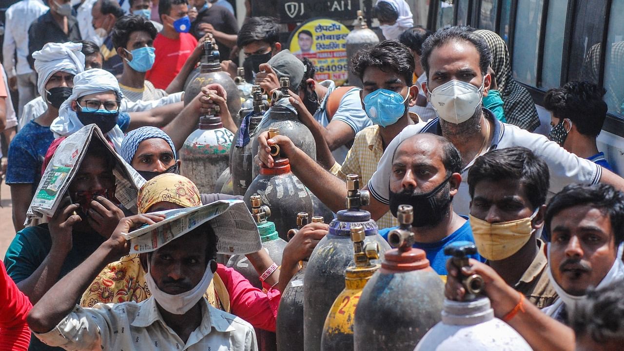 Family members of Covid-19 patients wait for their turn to refill empty oxygen cylinders, at a plant in Kanpur. Credit: PTI File Photo