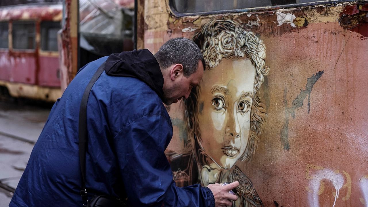 French street-artist Christian Guemy, known as C215, paints one of his works next to a metro station and food market that were badly damaged by a Russian strike in Kyiv. Credit: AFP Photo