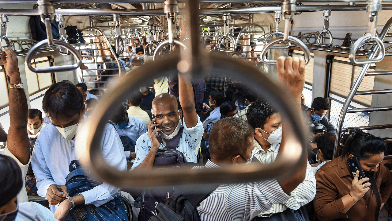 People ride a local train wearing masks as a precaution against the coronavirus. Credit: PTI Photo