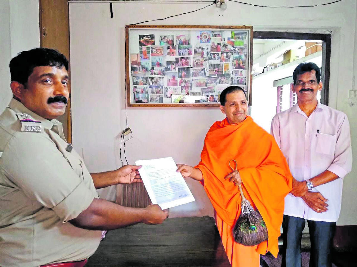 Swasthisri Charukeerthi Bhattaraka Pandithacharayavariya Swami of Jain Math, Moodbidri, receives a notice on the use of loudspeakers from Moodbidri Station House Officer (SHO) Niranjan on Wednesday.
