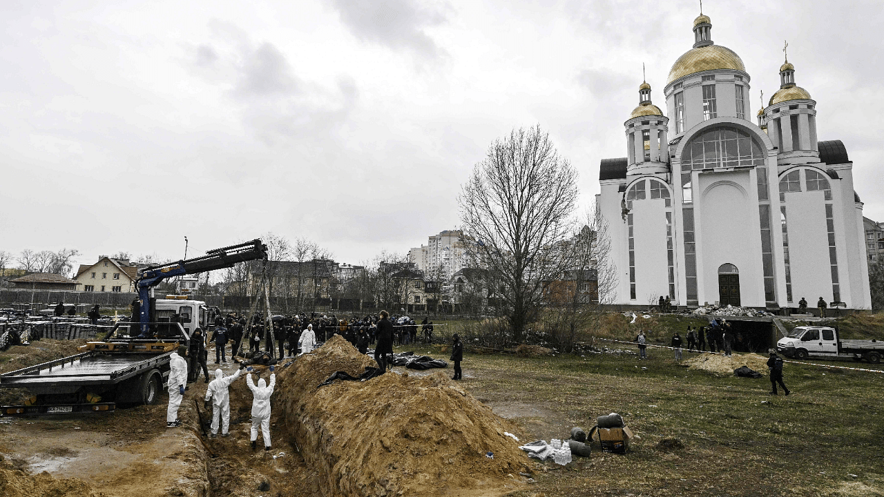 Ukrainian investigators exhume bodies from a mass grave in the gardens of the St Andrew church in the town of Bucha. Credit: AFP Photo