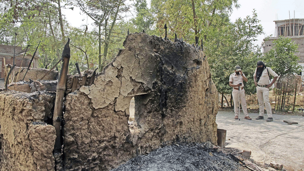 Security personnel stand guard near a damaged house at Bogtui village, in Birbhum district. Credit: PTI Photo