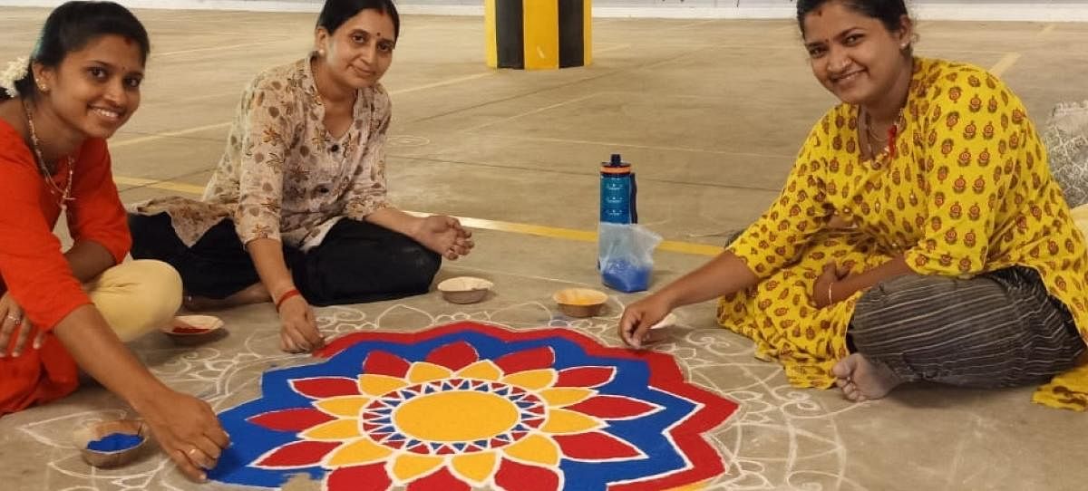 Women give a final touch to a rangoli during Police Habba 2022 held in Mangaluru on Saturday. DH Photo