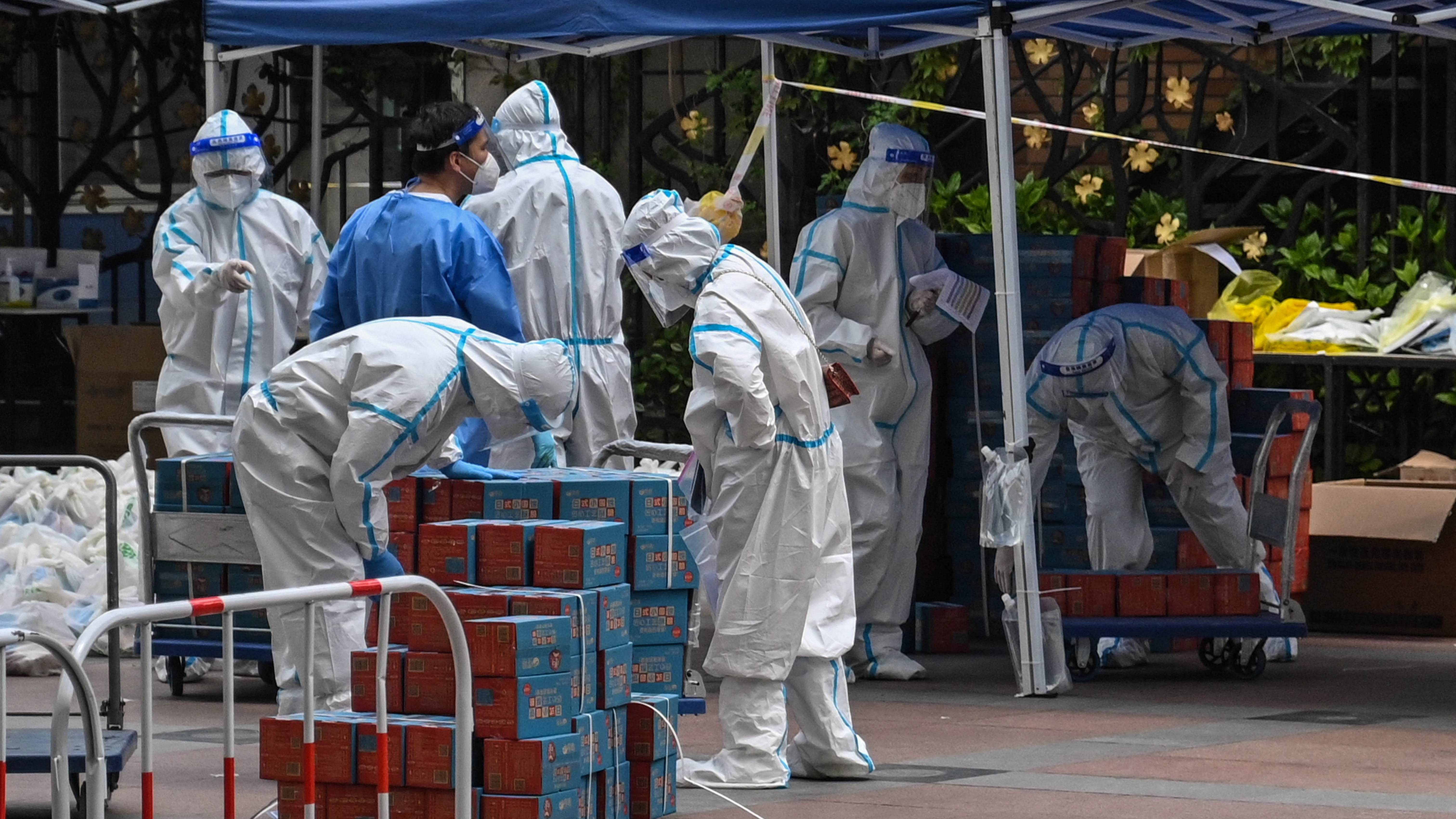 Workers wearing personal protective equipment (PPE) are seen next to food delivered by the local government for residents in a compound during a Covid-19 lockdown in the Jing'an district in Shanghai. Credit: AFP File Photo