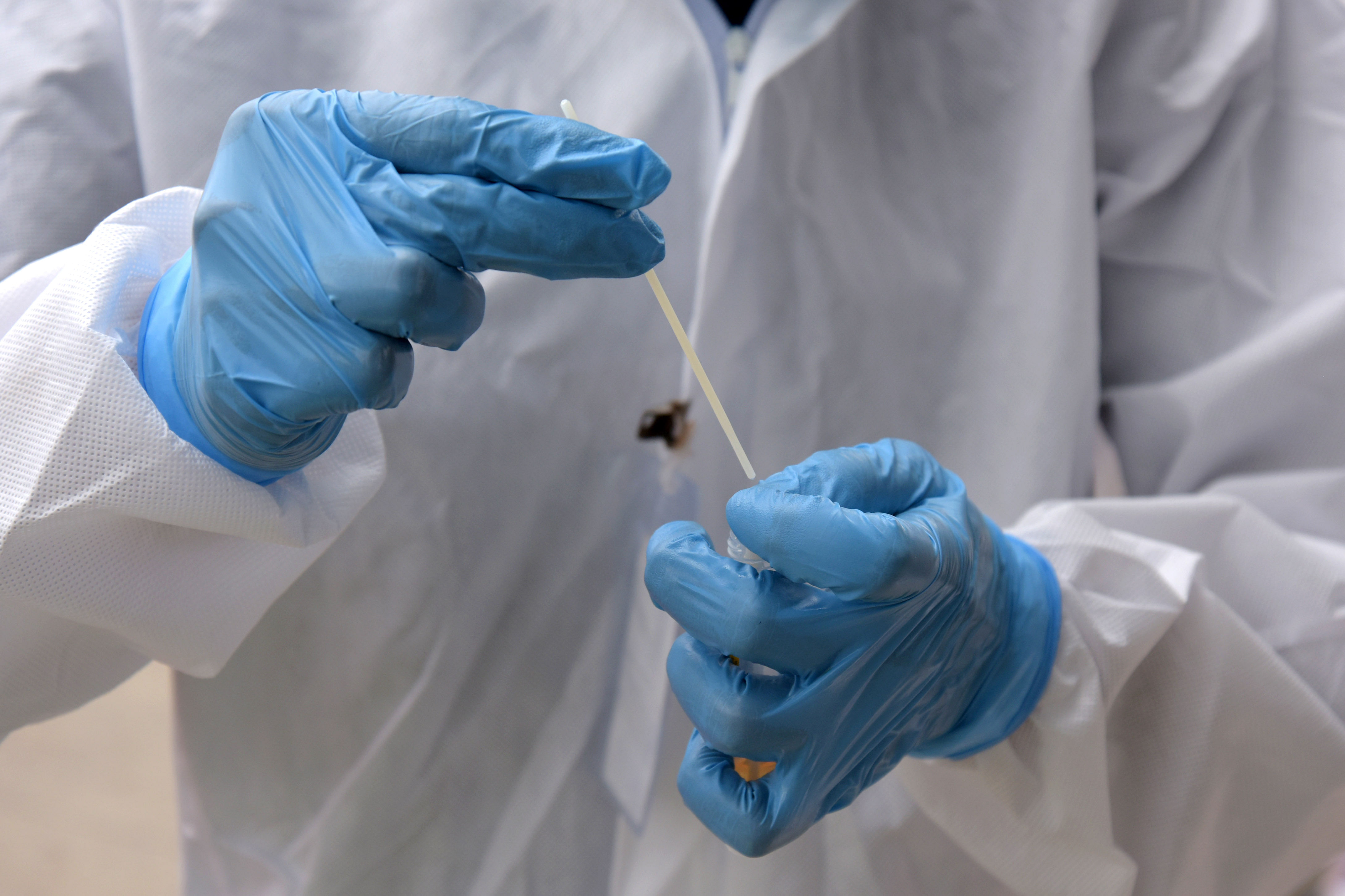 A healthcare worker collects swab samples for coronavirus from people at KSRTC bus stand. Credit: DH Photo