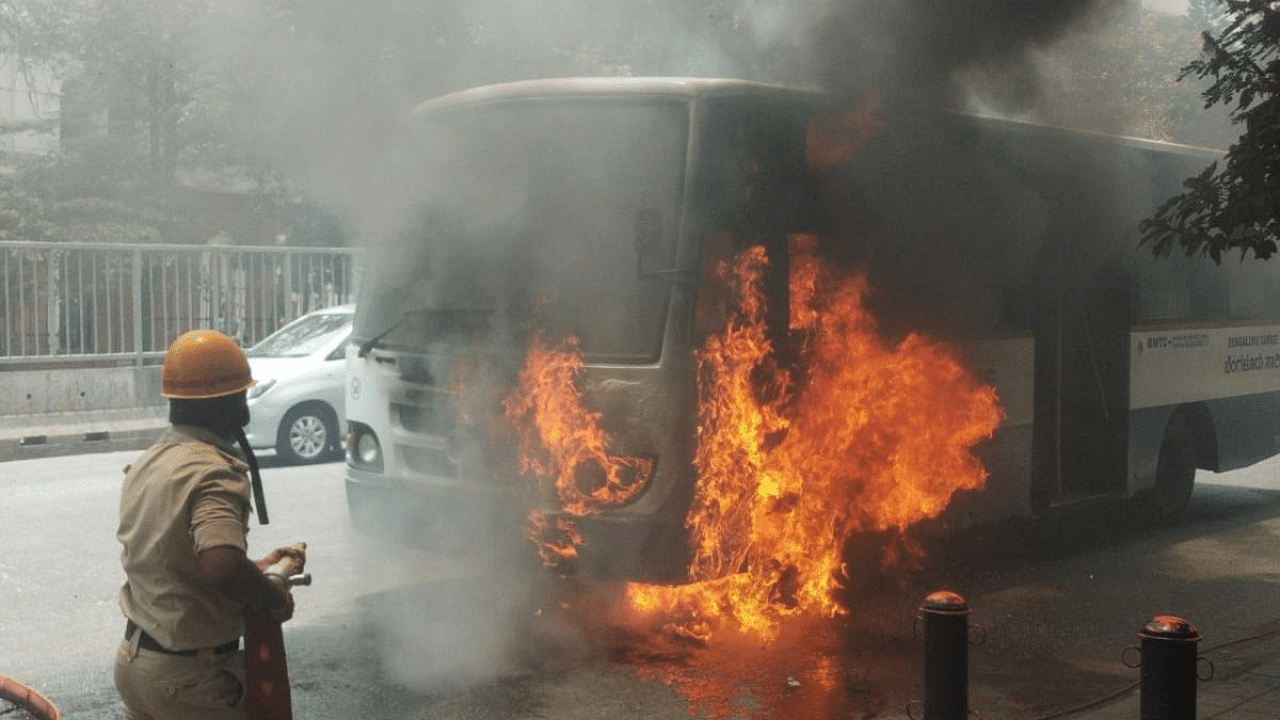 A fire and emergency services personnel douses flames after a BMTC bus caught fire on Seshadri Road in the city on Saturday. Credit: DH Photo