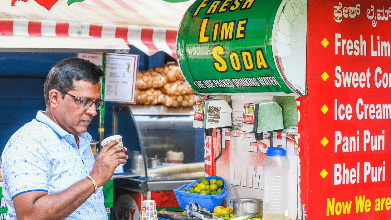 A man beats the heat with a glass of lime soda at a juice stall in the city. Credit: DH Photo