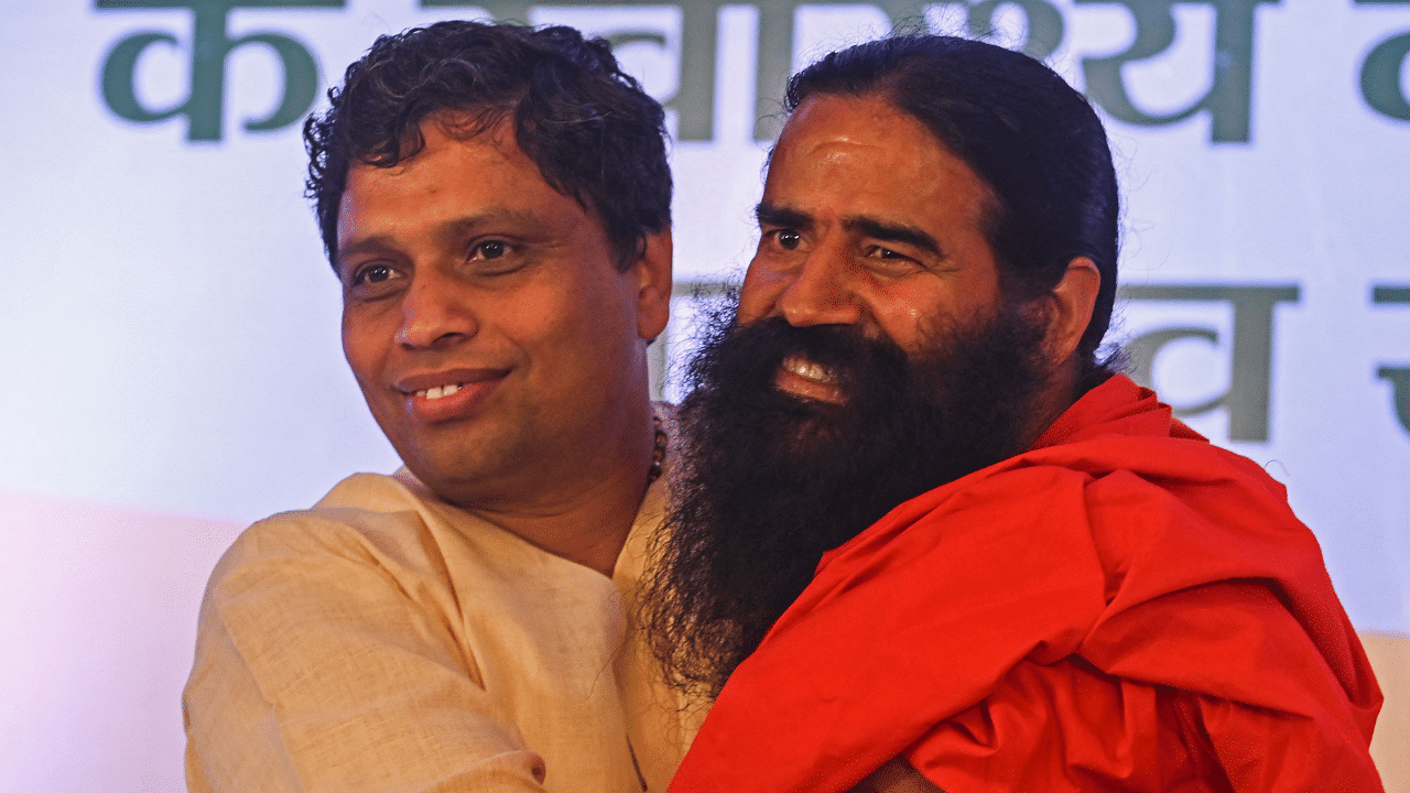 Patanjali Ayurveda managing director and chairman of Ruchi Soya Industries Limited (RSIL) Acharya Balkrishna (L) and Indian yoga guru and non-executive director of RSIL Baba Ramdev. Credit: AFP Photo