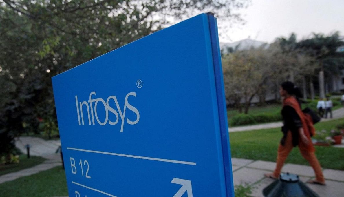 FILE PHOTO: An employees walks past a signage board in the Infosys campus at the Electronics City IT district in Bangalore. Credit: Reuters