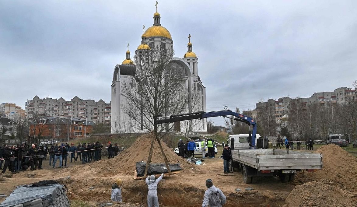 Journalists gather as bodies are exhumed from a mass-grave in the grounds of the St. Andrew and Pyervozvannoho All Saints church in the Ukrainian town of Bucha, northwest of Kyiv. Credit: AFP