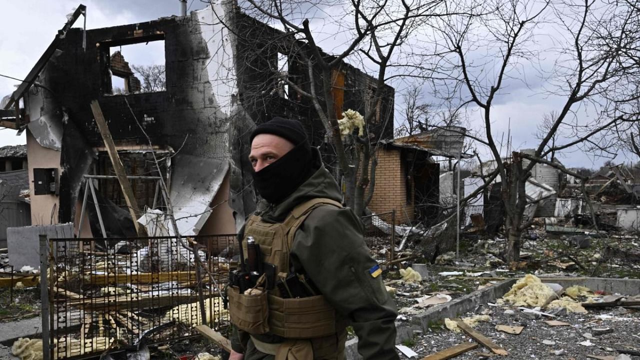A member of the Ukrainian territorial defense forces walks in front of a destroyed house in Bohdanivka village, northeast of Kyiv, on April 12, 2022. Credit: AFP Photo