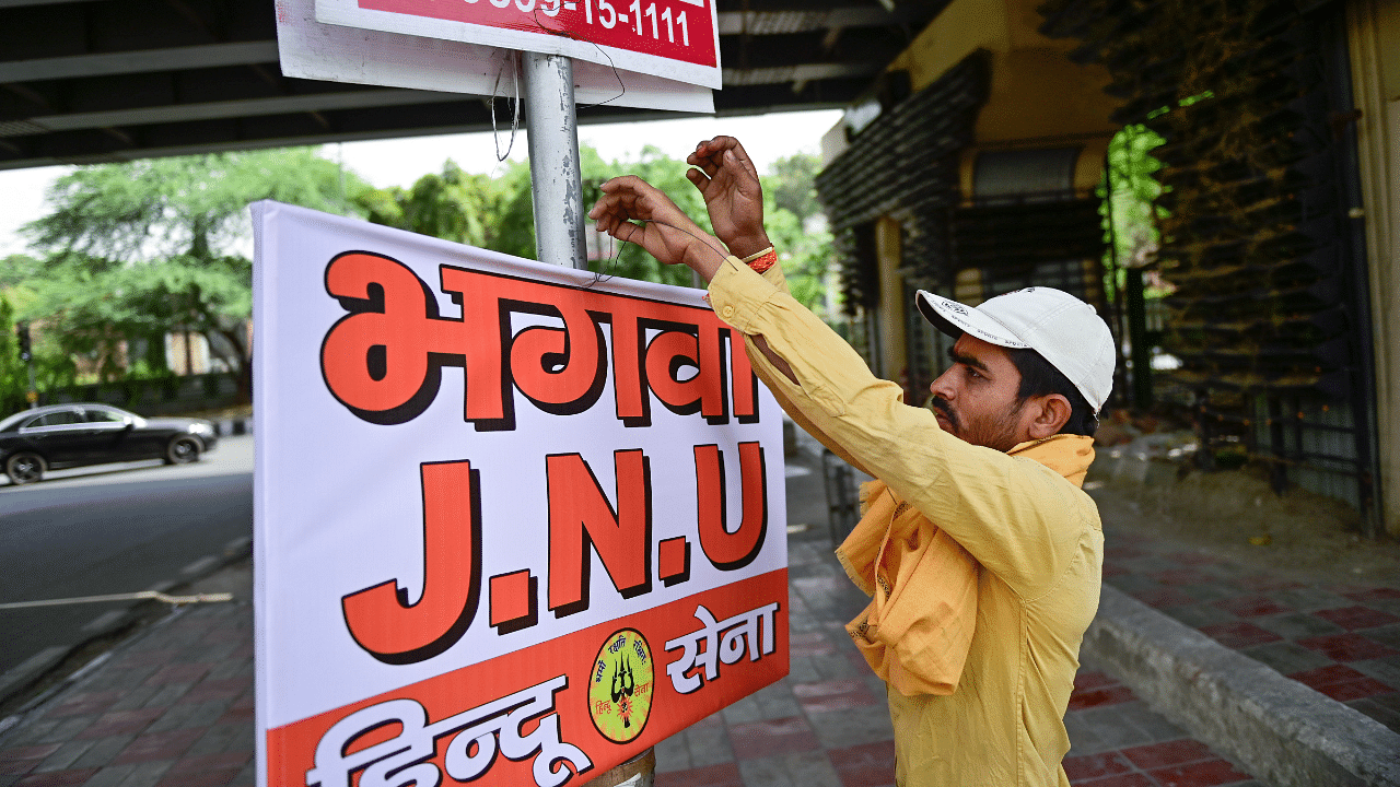A Delhi Police personnel removes saffron flags and posters near JNU in New Delhi. Credit: PTI Photo