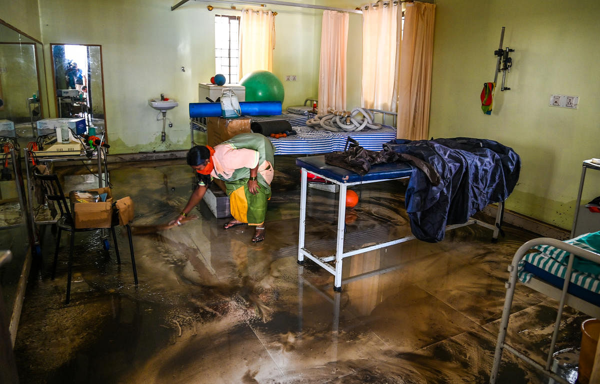 A BBMP worker clears the flood water from a hospital at Kamakya Layout after a stormwater drain in Chikkalsandra ward overflowed following a sharp spell of showers on Thursday evening. Credit: DH Photo