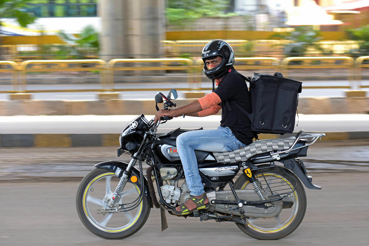 A delivery executive zooms across the road to reach his destination in Bengaluru on Saturday, August 28, 2021. Credit: DH Photo