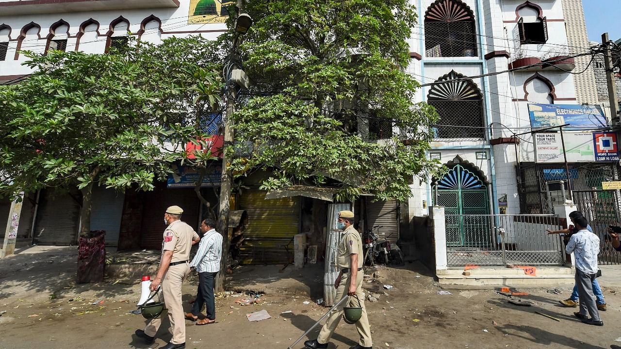 Security personnel stand guard at the entrance of a mosque after clashes broke out between two communities during a Hanuman Jayanti procession on Saturday, at Jahangirpuri. Credit: PTI Photo